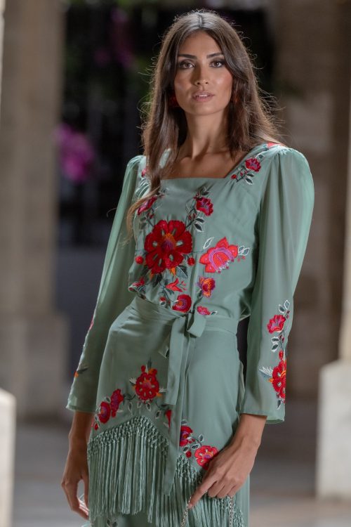 Modelo vistiendo conjunto Fino de Káhyra, bordado de flores y con flecos, falda y top, disponible en color negro, beige y verde.