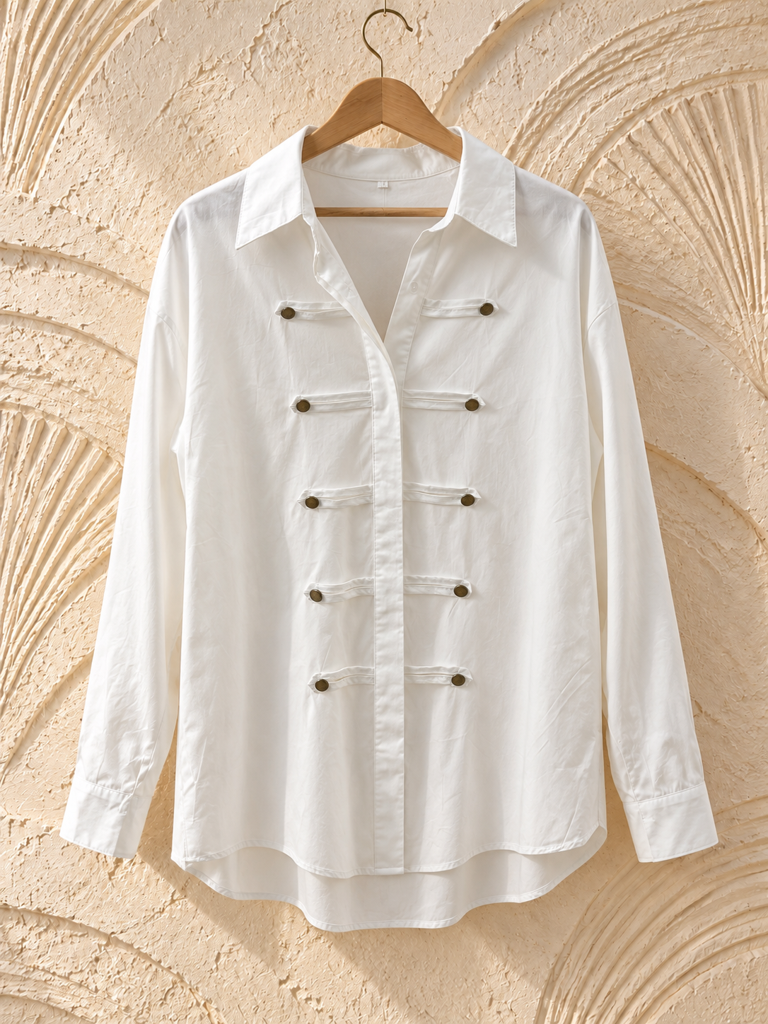 Blusa blanca con trabillas y botones dorados, vista frontal