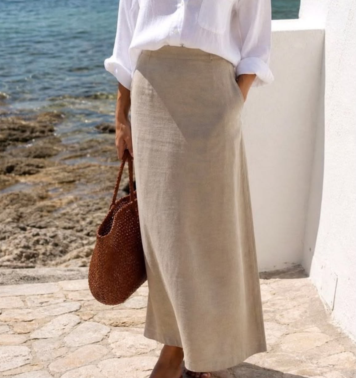 Mujer con falda larga beige y bolso granate